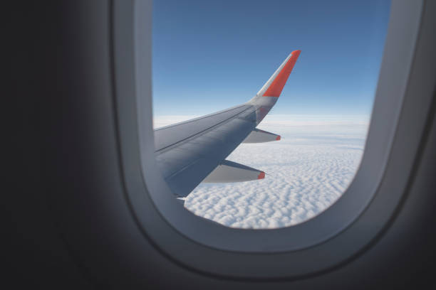 istock View from inside airplane window. Looking outside at the airplane wing seeing clouds and a blue sky. 979441932