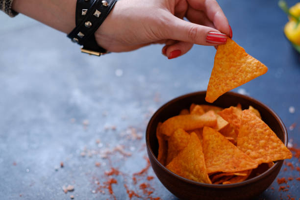 istock junk fast food eating nacho chips hand hold crisp 979442454