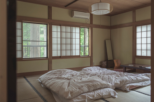 interior inside the bedroom of old style Japanese Ryokan room with white futon mattress on the tatami mat.