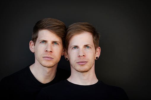 twin brothers portrait headshot on black background.