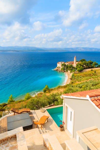 View of famous Dominican monastery on beach in Bol town with holiday apartment terrace in foreground, Brac island, Croatia Dalmatia is a narrow belt of the east shore of the Adriatic Sea, stretching from island of Rab in the north to the Bay of Kotor in the south. brac island stock pictures, royalty-free photos & images