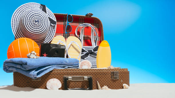 istock Suitcase with sand and travel supplies 979459590