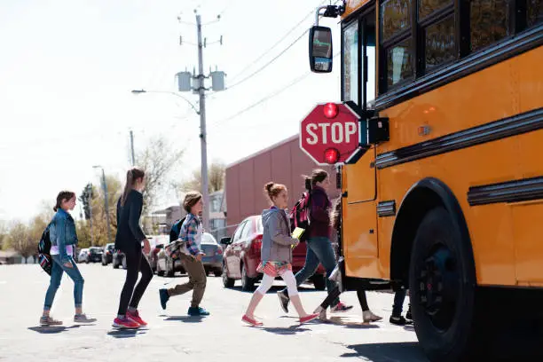 Photo of Group of elementary school kids getting in a school bus at school's out.