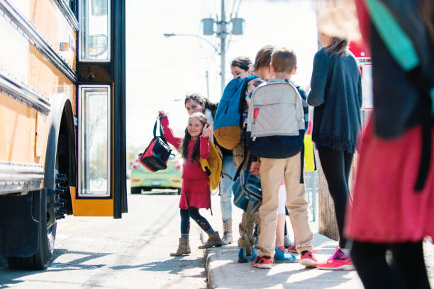 istock Group of elementary school kids getting in a school bus at school's out. 979468618
