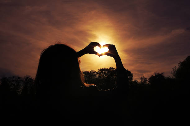 istock Young woman making heart with her hands at sunset 979486448