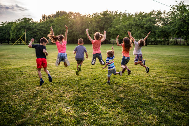 istock Back view children jumping in public park 979487910