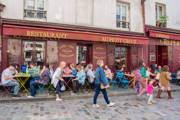 Paris / France - May 16, 2018: People dine outdoors at a cafe at the famous Place du Tertre, a public plaza and popular tourist site near the Sacré Coeur cathedral.