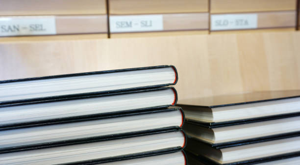 istock Book with black cover stacked, old library catalog blurred in the background 979496678