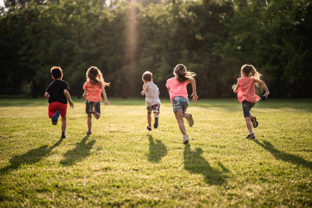 groupe de vue arrière des enfants qui courent dans la nature - childrens park photos et images de collection