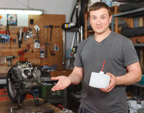 Portrait of man master who is repairing motobike in the workshop.