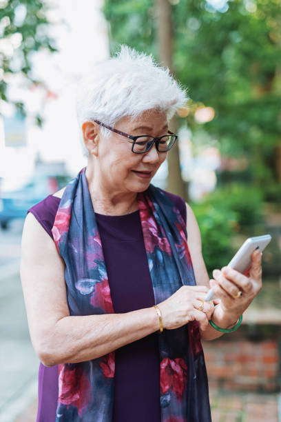 istock Senior woman in the city using phone for text messaging 979511224