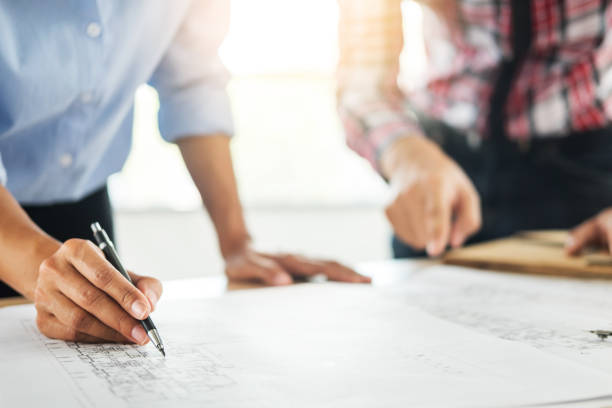 istock Midsection Of Colleagues Working On Blueprint 979512902
