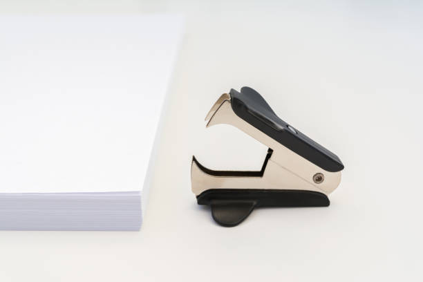istock stack of white office paper and a black anti-stapler on a white background, close-up abstract background 979537482