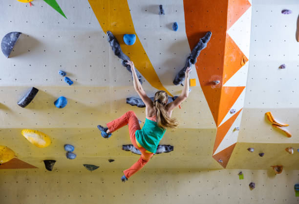 istock Young woman falling down while bouldering in climbing gym, hands slipping 979543398