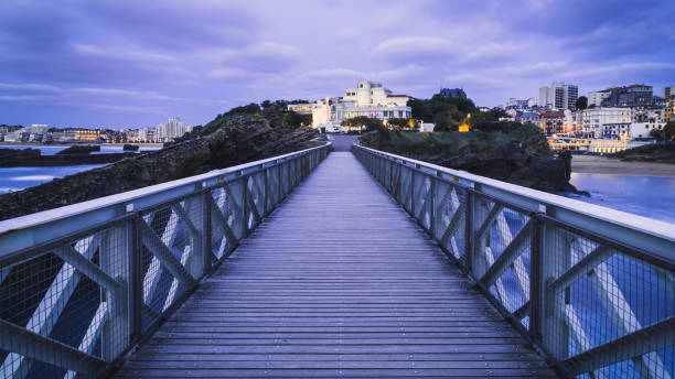 View of the bridge to Rocher de la Vierge at twilight, looking back towards the town and the aquarium.