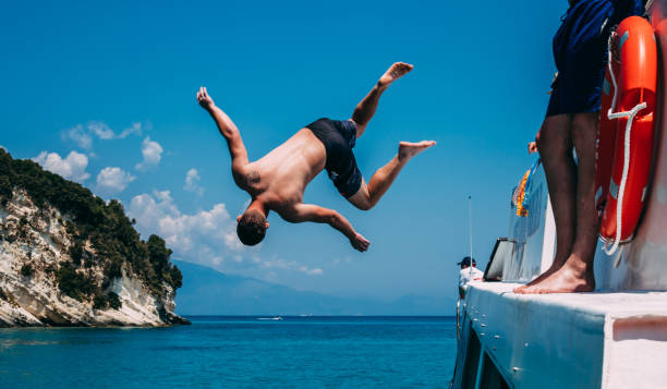 istock Young Man Jumping in the Sea from a Boat 979550338