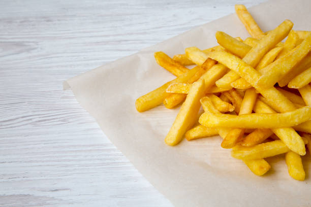 istock French fries on a white wooden surface, closeup. 979562404