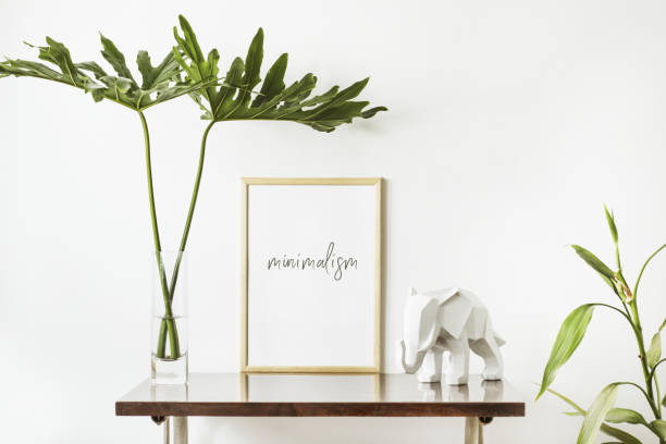 istock The stylish interior with mock up poster frame, leafs and elephant sculpture. The minimalizm concept of space. 979566994