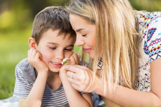 istock Mother and son smelling flower in park 979567204