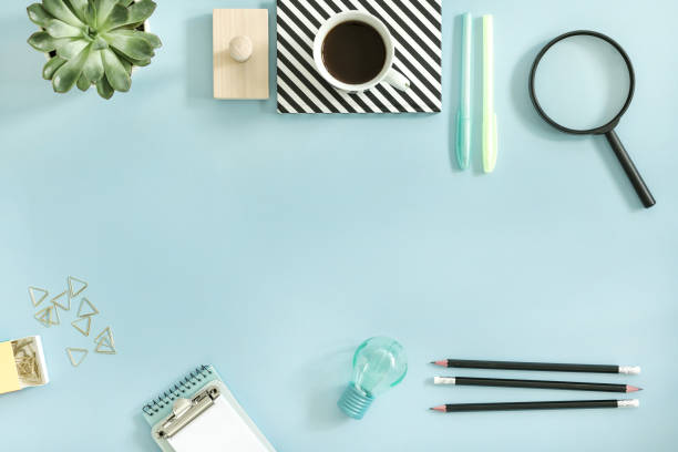istock Creative desk with office accessories, cup of coffe and suculent. Blue background with copy space. Solutions for project. 979571110