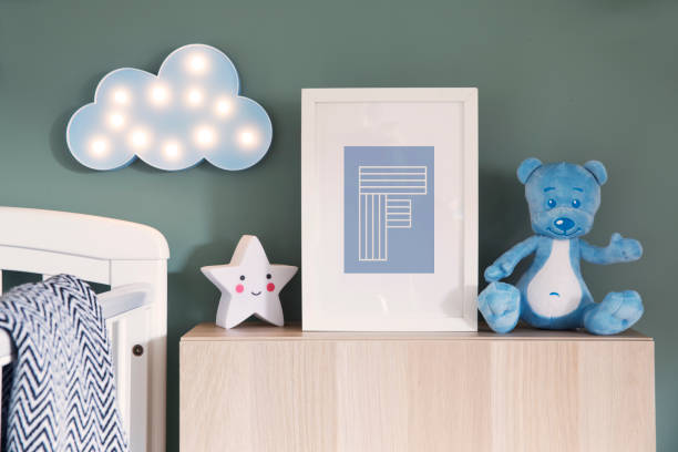 Stylish nursery interior with mock up photo frame, teddy bear, star and blue cloud. Green background wall. Modern baby interior with green background wall - cute nursery. nursery bedroom photos stock pictures, royalty-free photos & images