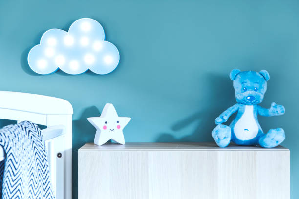 istock Stylish nursery interior with photo frame, teddy bear, star and blue cloud. Blue background wall. 979584910