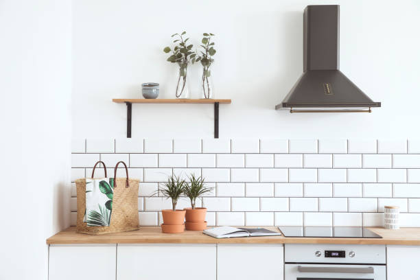 istock Modern and design scandinavian kitchen with plants, accessories and straw bag. Sunny and bright space with white brick wall. 979585034