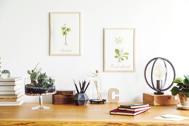 istock Vintage, creative home office interior with wooden desk, notebooks, romantic illustrations of plants, table lamp and office accessories. Stylish space for freelancer. 979588304
