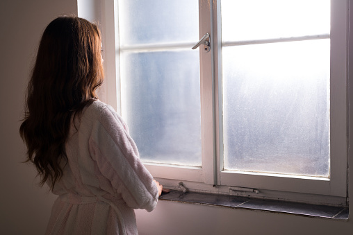 Woman suffering from cancer looking through hospital window.