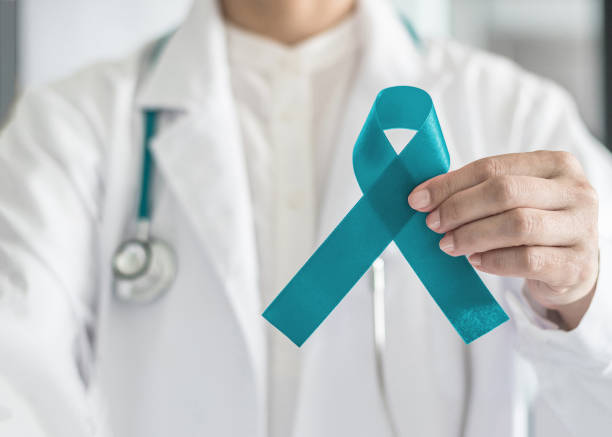 Teal awareness ribbon in doctor's hand, symbolic bow color for supporting patient with Ovarian Cancer, PCOS and PTSD Illness Teal awareness ribbon in doctor's hand, symbolic bow color for supporting patient with Ovarian Cancer, PCOS and PTSD Illness human papilloma virus photos stock pictures, royalty-free photos & images