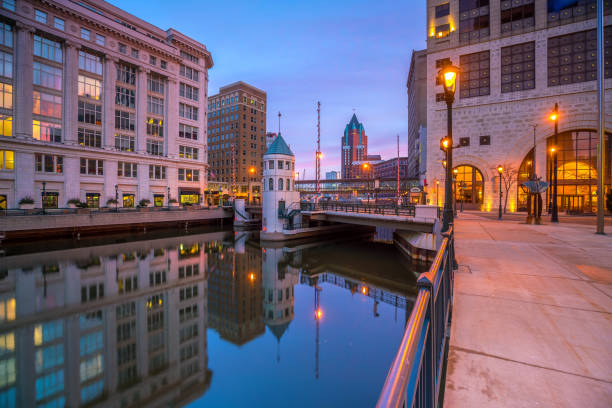 Downtown Milwaukee skyscrapers (prominently showing Milwaukee Center) with the Milwaukee River and orange colored trees during Autumn in the foreground.