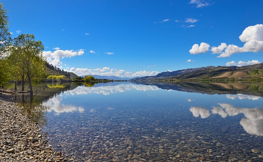 A mirror reflection of a beautiful spring morning was captured in the perfectly still waters of Lake Dunstan in Cromwell, New Zealand
