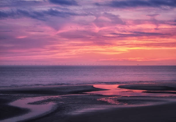 hermosa cerca de crepúsculo oscuro sobre un tranquilo mar plano con cielo púrpura y azul nubes reflejada en el agua en la playa - horizon over water england uk summer fotografías e imágenes de stock