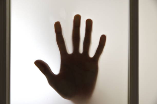 istock horror silhouette and hand behind glass 979627082