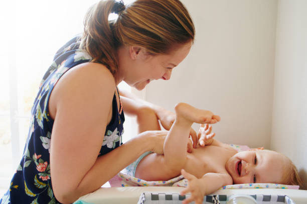 Bonding with baby happens anytime even during a diaper change Shot of a young woman changing her adorable baby girl’s diaper on a table at home Diaper stock pictures, royalty-free photos & images