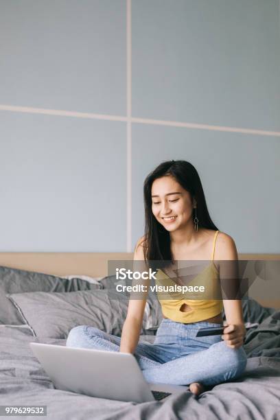 Woman Sitting On Bed Using Credit Card For Online Shopping Stock Photo - Download Image Now