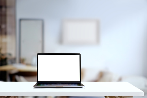 Mockup blank screen laptop on desk in living room background.