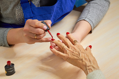 Esteticista aplicando barniz rojo para uñas de la mujer. photo