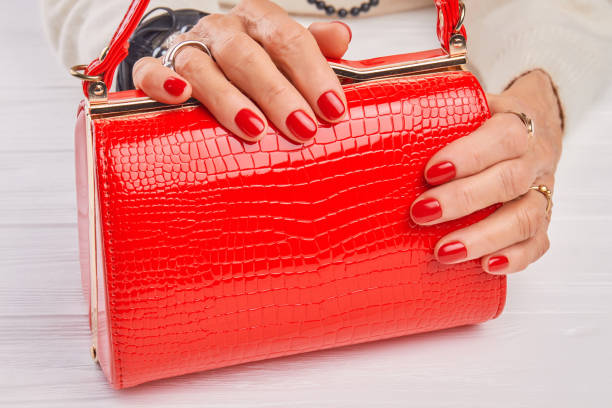istock Red lacquered bag in female hands. 979635362