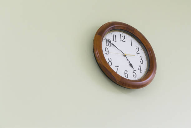 istock white and brown wooden clock wall on green concrete wall background 979651286
