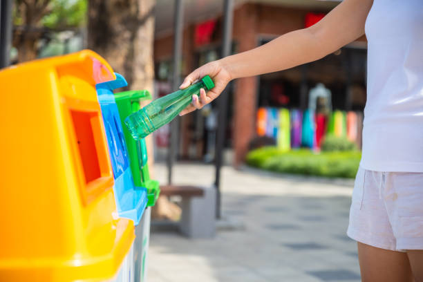 istock World Environment Day concept. Woman hand holding and putting plastic bottle waste into garbage trash. 979674596