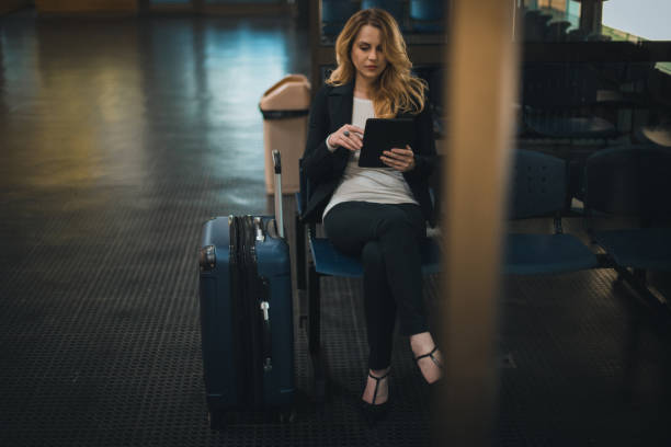istock Beautiful young businesswoman using digital tablet while waiting for her flight 979675280
