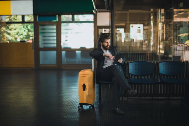 istock Fashionable businessman with a suitcase using digital tablet 979675662