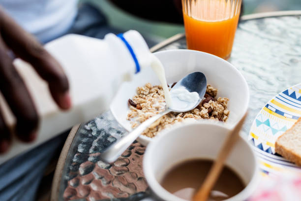 Closeup of hand pouring milk into cereal