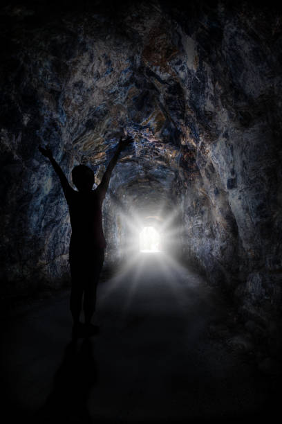 istock Woman Stands Inside Tunnel With Blinding Light 979698268