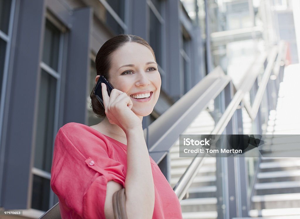 Woman talking on cell phone on sunny stairs  20-24 Years Stock Photo