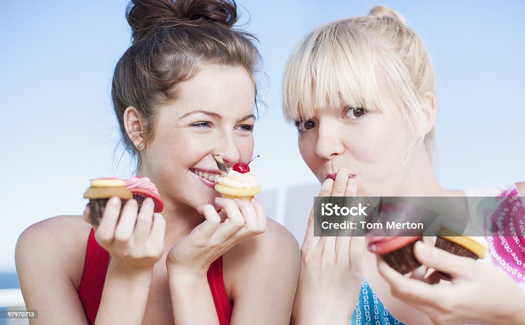 Kobiety jedzenie cupcakes - Zbiór zdjęć royalty-free (Jedzenie na słodko)