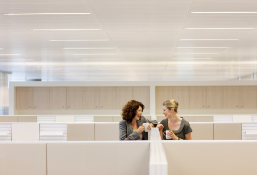 Mujeres de negocio con café gossiping en cubículos de oficina photo