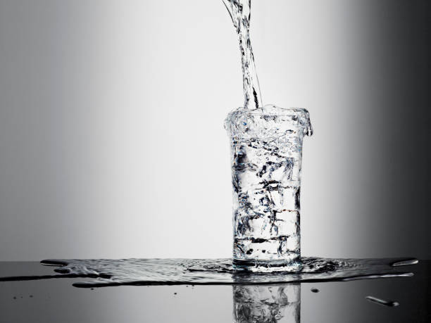 acqua versare nel bicchiere e traboccante - pieno foto e immagini stock