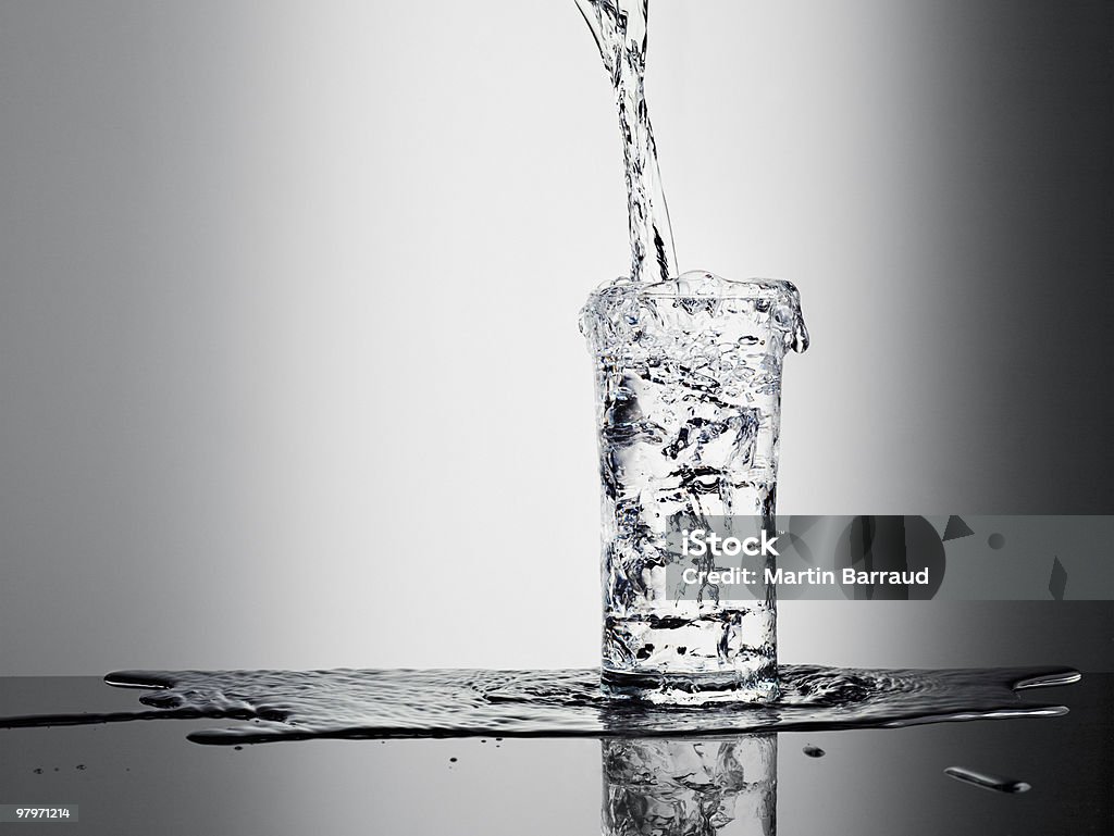 Water pouring into glass and overflowing  Water Stock Photo